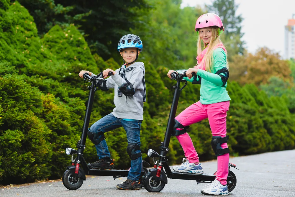 Happy kids standing on electric scooter