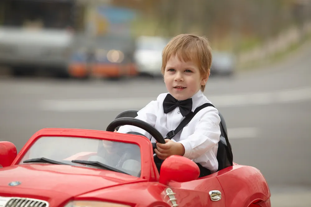 Boy in a red toy car in the street