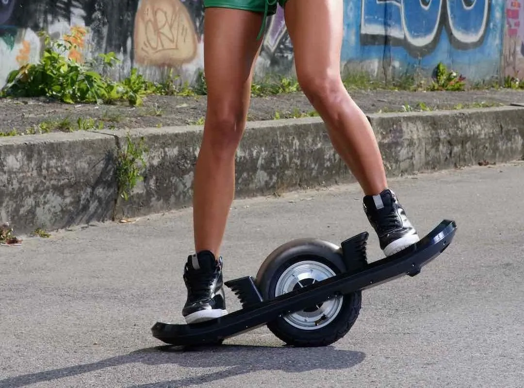 Teen riding electric onewheel skateboard having fun in the street